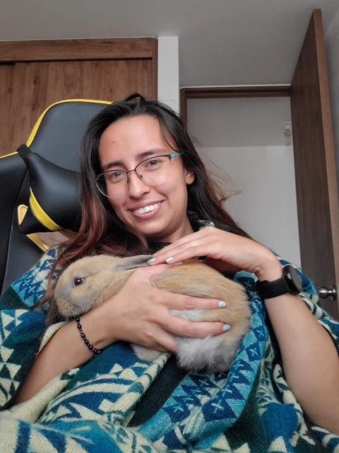 Coco en brazos de una persona sentada en una silla de escritorio.
